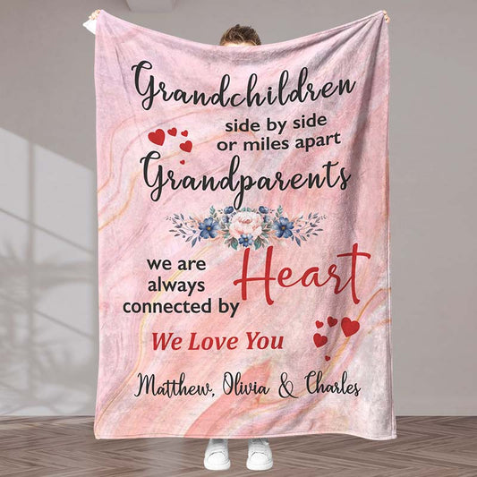 A pink blanket with a meaningful message for grandparents from grandchildren, with a heart and floral design, held by a person