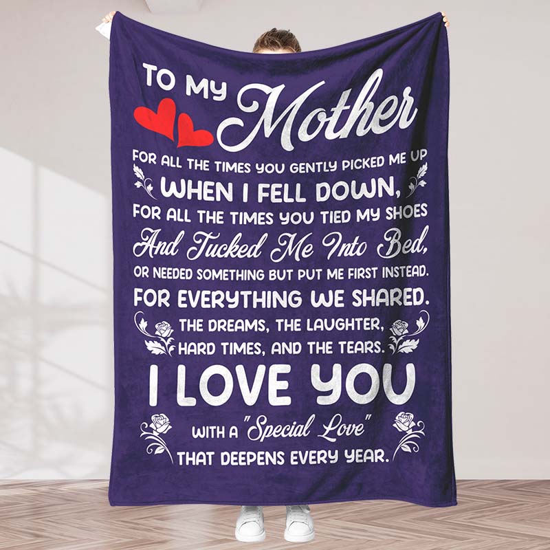 Purple fleece blanket featuring a white sentimental message for a mother, held by a person, in an indoor background.