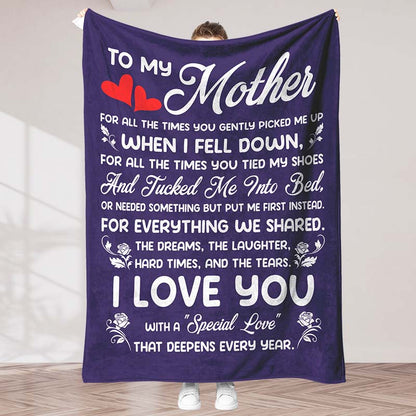 Purple fleece blanket featuring a white sentimental message for a mother, held by a person, in an indoor background.