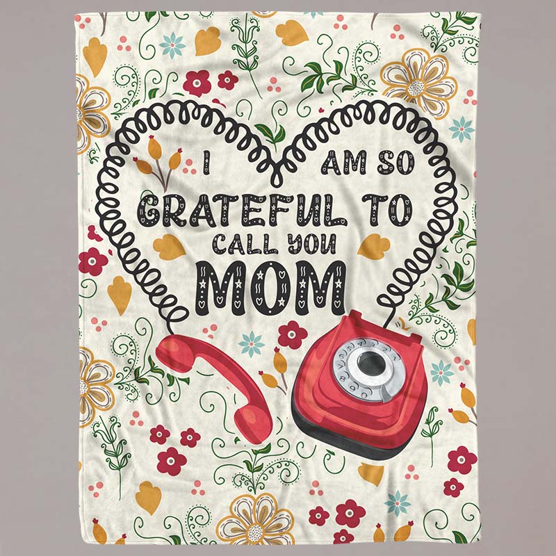 Blanket with floral design and text 'I am so grateful to call you Mom' featuring a red phone, on a grey background