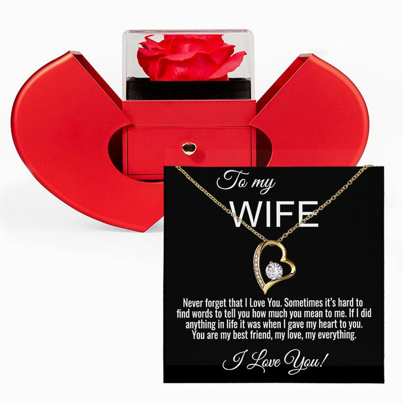 A red heart-shaped jewelry gift box with a red rose displayed inside, shown alongside a black gift card addressed 'To my WIFE' featuring a gold heart necklace with a clear heart-shaped gemstone and a sentimental message.