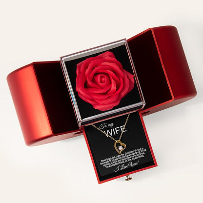 A red rose keepsake box with a heart-shaped gold pendant necklace displayed on a black card that reads 'To my WIFE'.