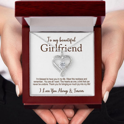 Hand holding a jewelry box with a heart-shaped diamond necklace and the card message: 'To my beautiful girlfriend, I love you for always and forever