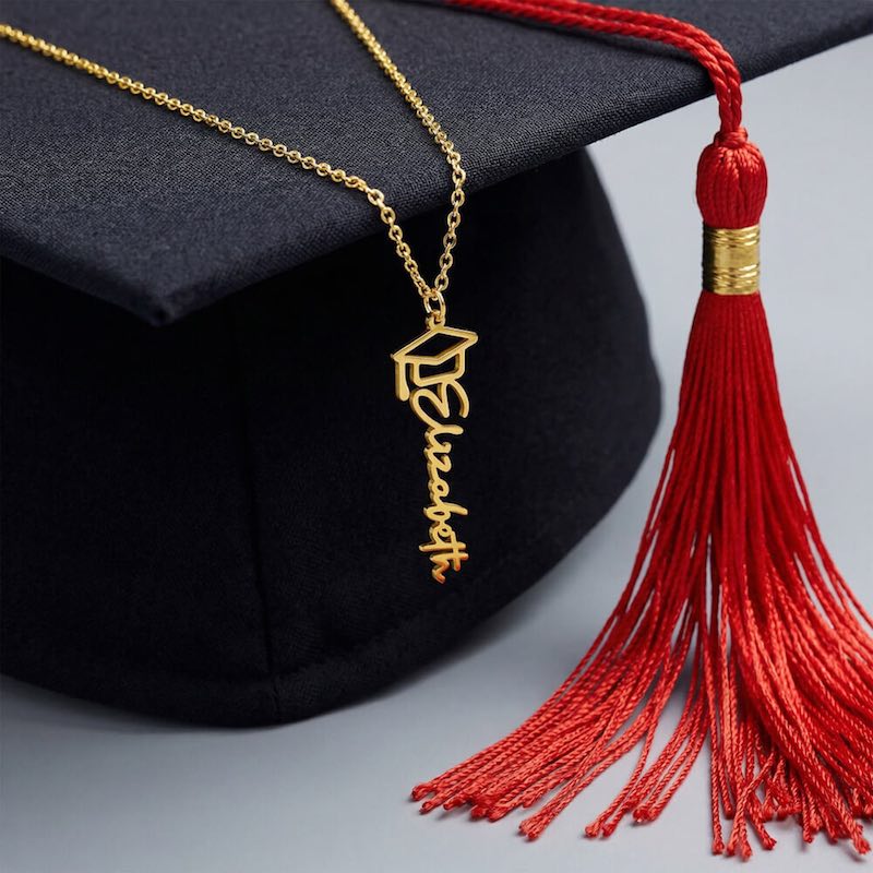 Gold graduation cap necklace with red tassel on a black graduation cap