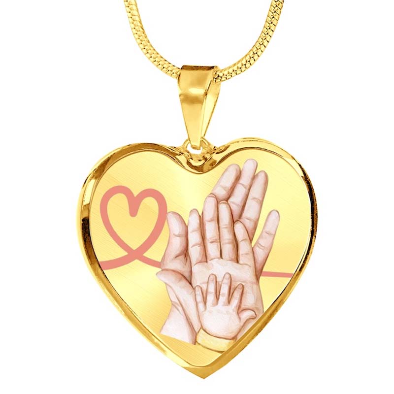 Gold heart-shaped pendant with hands and a pink heart design on a white background