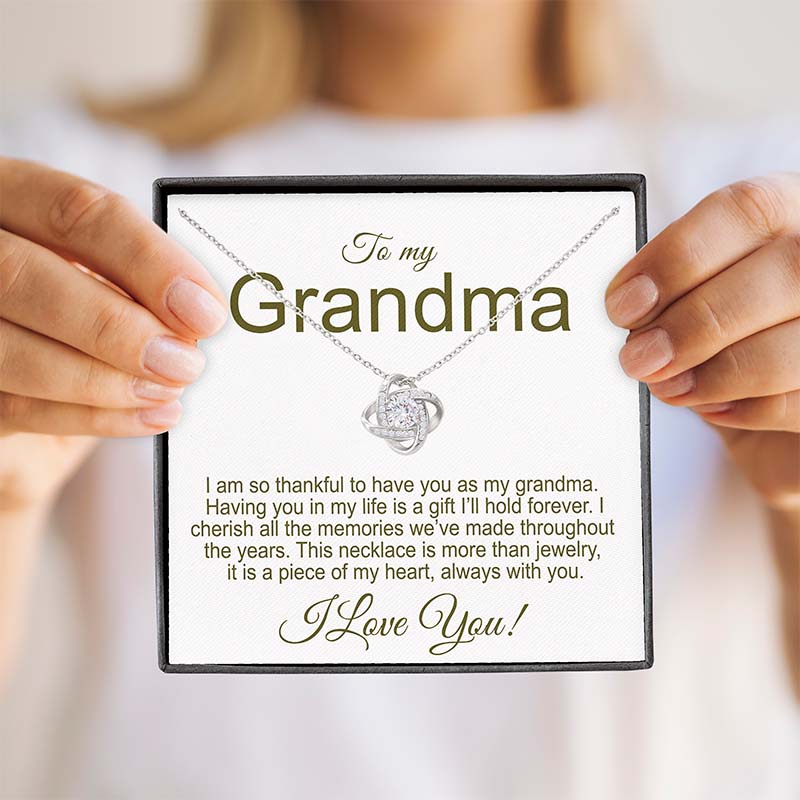 Grandmother Gift: Love knot necklace in white gold finish with sentimental message card for grandma held by hands.