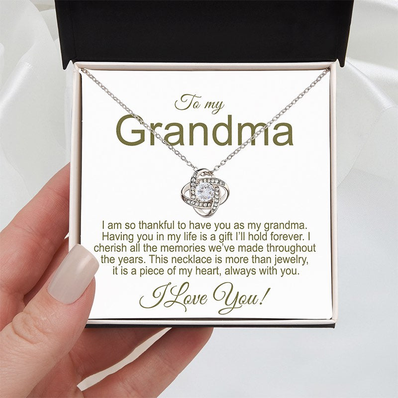 Grandmother Necklace: Knot necklace 14K White Gold Finish in a two tone box with a sentimental message for a grandma, held by a hand on a white silk background.