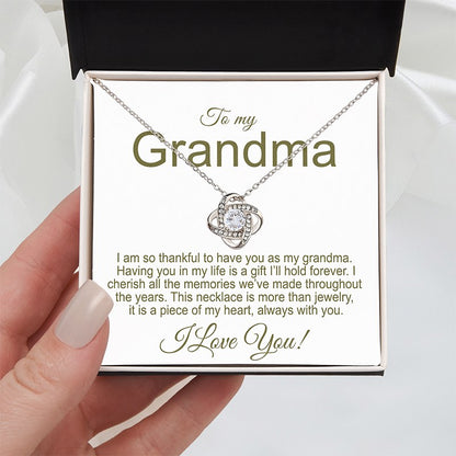Grandmother Necklace: Knot necklace 14K White Gold Finish in a two tone box with a sentimental message for a grandma, held by a hand on a white silk background.