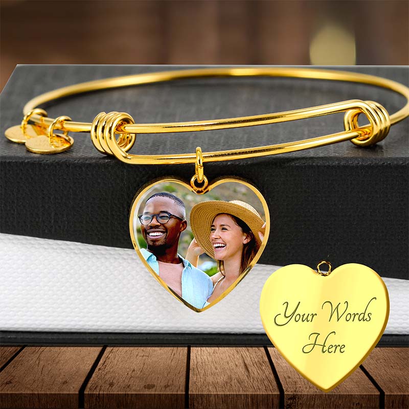 Gold bracelet with heart-shaped charms featuring a couple's photo and customizable text on a wooden surface.