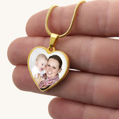 Heart-shaped pendant with a photo of a woman and a baby held between fingers