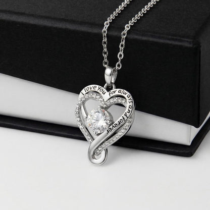 Heart-shaped silver necklace with a clear cubic zirconia stone on a black and white gift box.