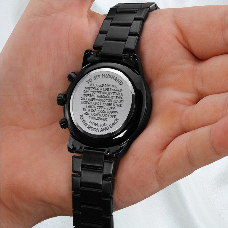 Mens watch with sentimental message engraving for husband kept by a hand against a white silk background.