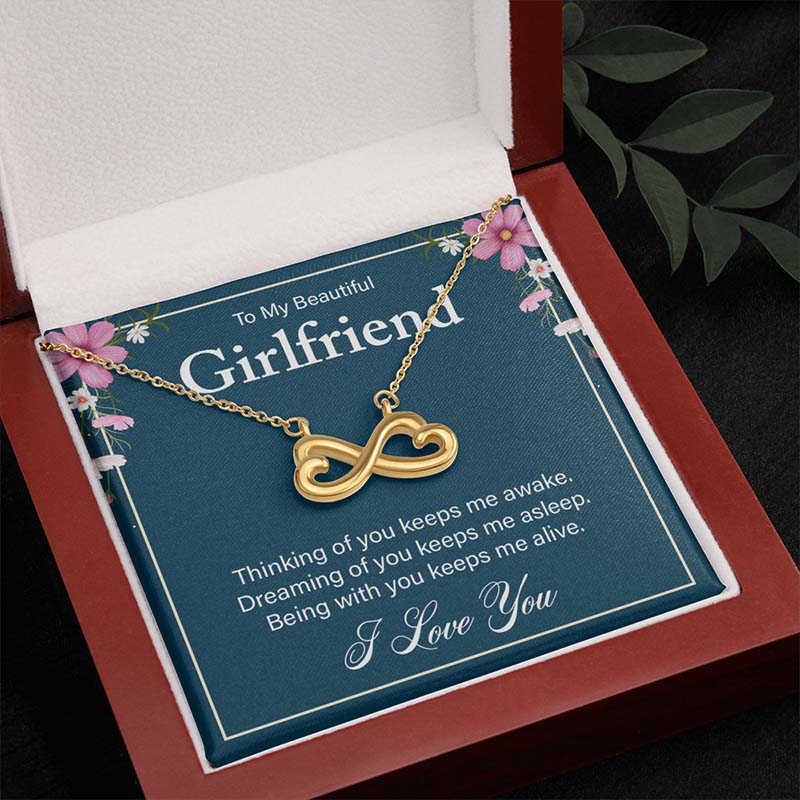 Gold infinity heart necklace on a “To My Beautiful Girlfriend” message card, displayed inside an open wooden luxury gift box.
