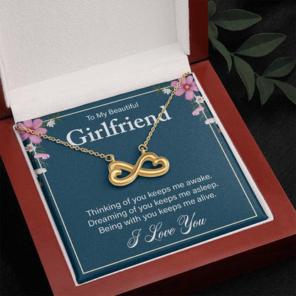 Gold infinity heart necklace on a “To My Beautiful Girlfriend” message card, displayed inside an open wooden luxury gift box.