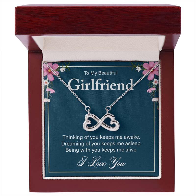 Silver infinity heart necklace displayed on a “To My Beautiful Girlfriend” message card inside an open luxury wooden gift box.