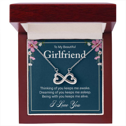 Silver infinity heart necklace displayed on a “To My Beautiful Girlfriend” message card inside an open luxury wooden gift box.