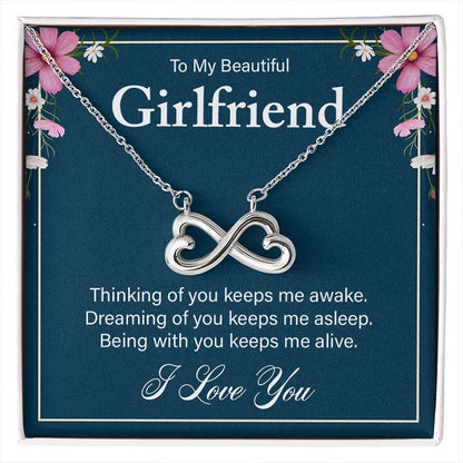 Silver infinity heart necklace on a blue gift card reading “To My Beautiful Girlfriend,” displayed in a gift box.