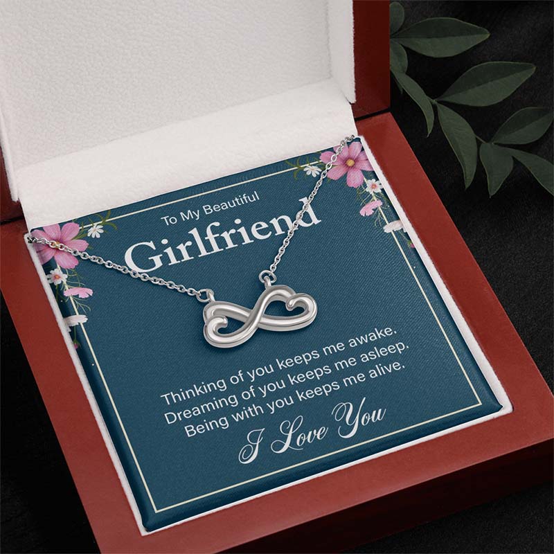 Silver infinity heart necklace on a “To My Beautiful Girlfriend” message card, displayed inside an open wooden luxury gift box.