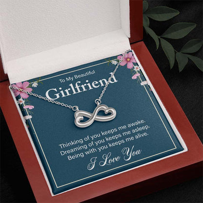 Silver infinity heart necklace on a “To My Beautiful Girlfriend” message card, displayed inside an open wooden luxury gift box.