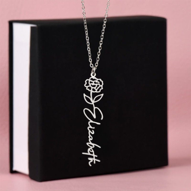 Silver necklace with January flower birth design and 'Elizabeth' engraving on a black box with pink background