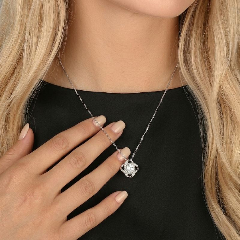 Silver Knot Necklace - woman wearing a silver knot necklace with a centered Zirconia stone against a black top.