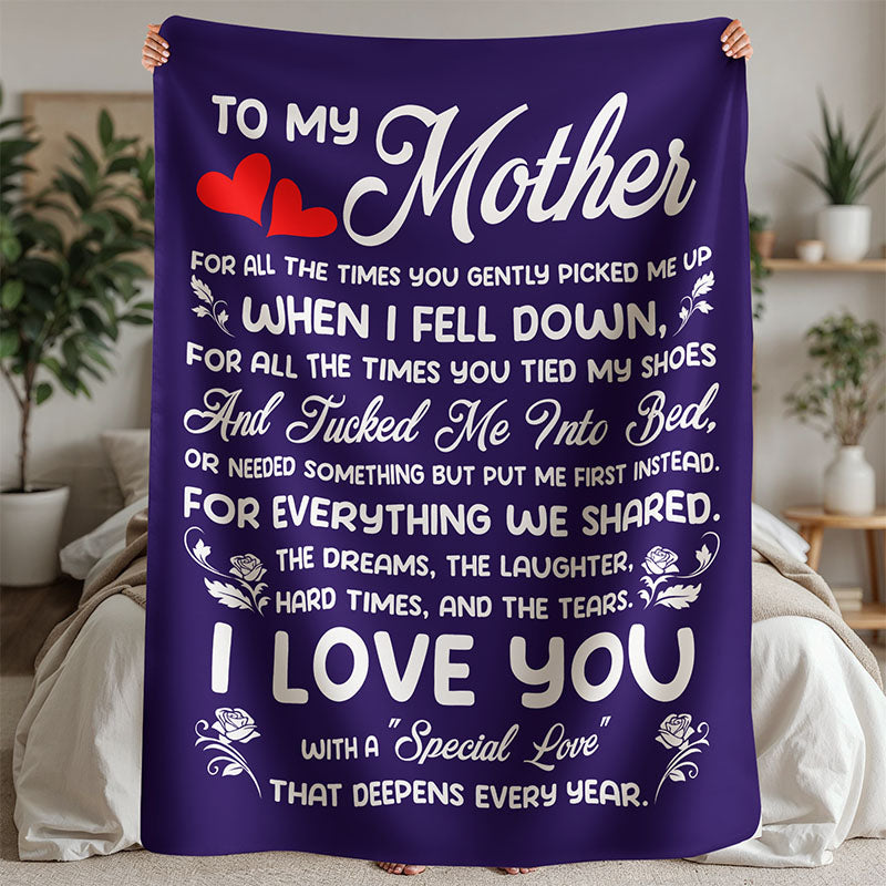 Purple fleece blanket, with a heartfelt message 'To My Mother' in white text, held by a person, in a bedroom setting.