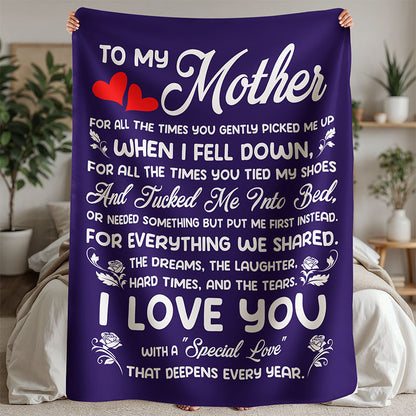 Purple fleece blanket, with a heartfelt message 'To My Mother' in white text, held by a person, in a bedroom setting.