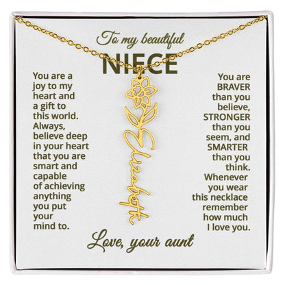 Gold necklace with daffodil flower design with engraved message on a white card for niece.