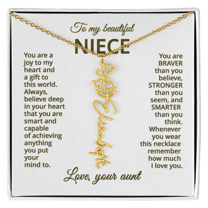 Gold name necklace and lily of the valley flower pendant with a sentimental message card for a niece on a white background.