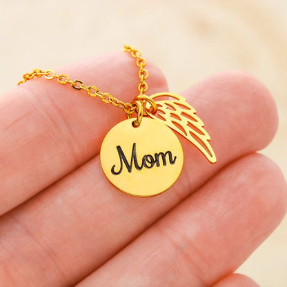Gold necklace with 'Mom' pendant held in a hand against a beige background