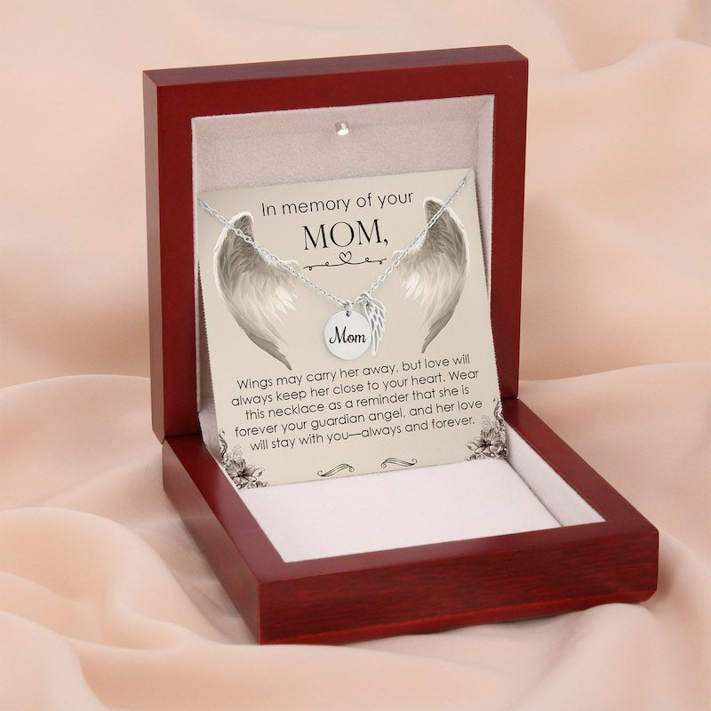 Silver angel wing necklace in a wooden box with a sentimental message for mom on a soft pink background