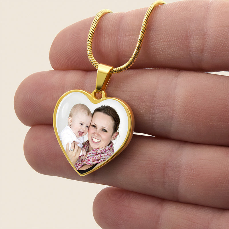 custom photo necklace: gold heart-shaped pendant with a photo of a woman and a baby held between fingers