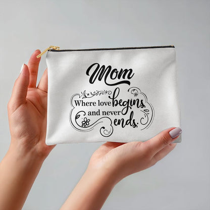 White pouch with 'Mom Where love begins and never ends' text held by a hand on a gray background