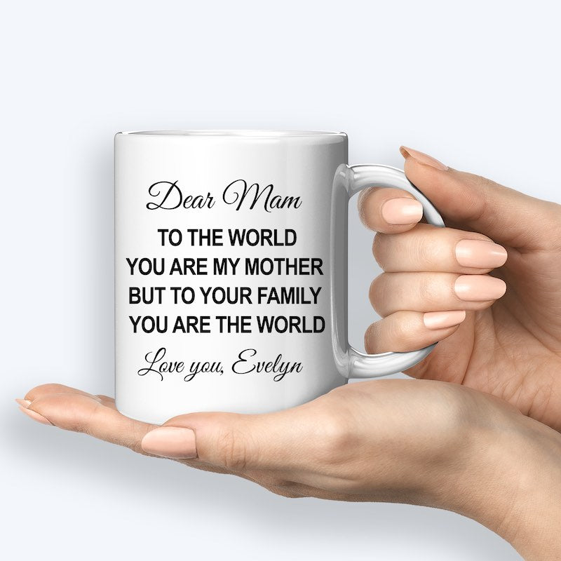 White ceramic mug featuring a heartfelt message for Mom, customized with the name "Evelyn," held by a hand.