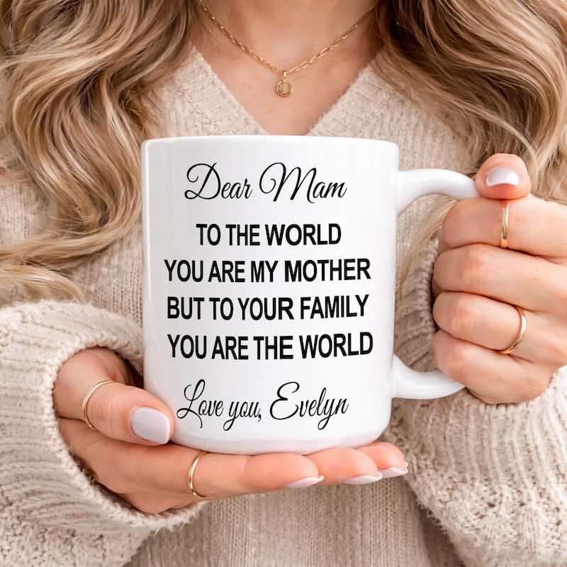 Personalized Mom Mug: woman holding a white ceramic mug featuring a heartfelt message for Mom, customized with the name "Evelyn," while wearing a cozy cream sweater.