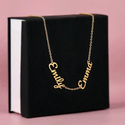 Gold name necklace with 'Emily' and 'Emma' pendants on a black box with pink background