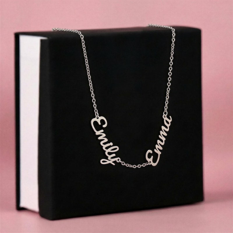 Silver necklace with 'Emily' and 'Emma' on a black box with a pink background