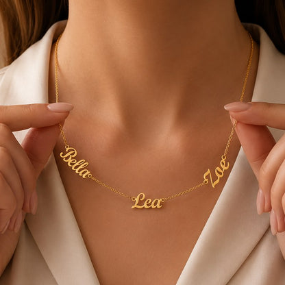 Gold name necklace with 'Bella', 'Lea', and 'Zoe' on a person wearing a white outfit.