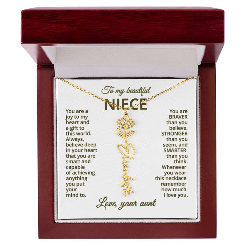 Gold name necklace and chrysanthemum  flower pendant on a card with sentimental message for niece on a white background  in a wooden box.