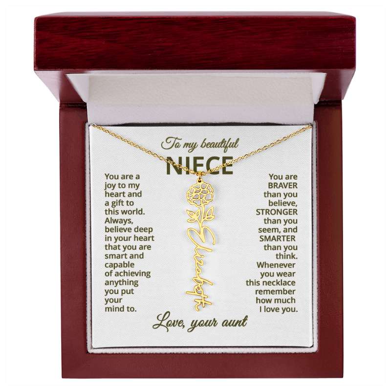 Gold name necklace and marigold flower pendant on a card with sentimental message for niece on a white background in a wooden box