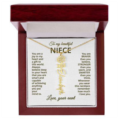 Gold name necklace and marigold flower pendant on a card with sentimental message for niece on a white background in a wooden box