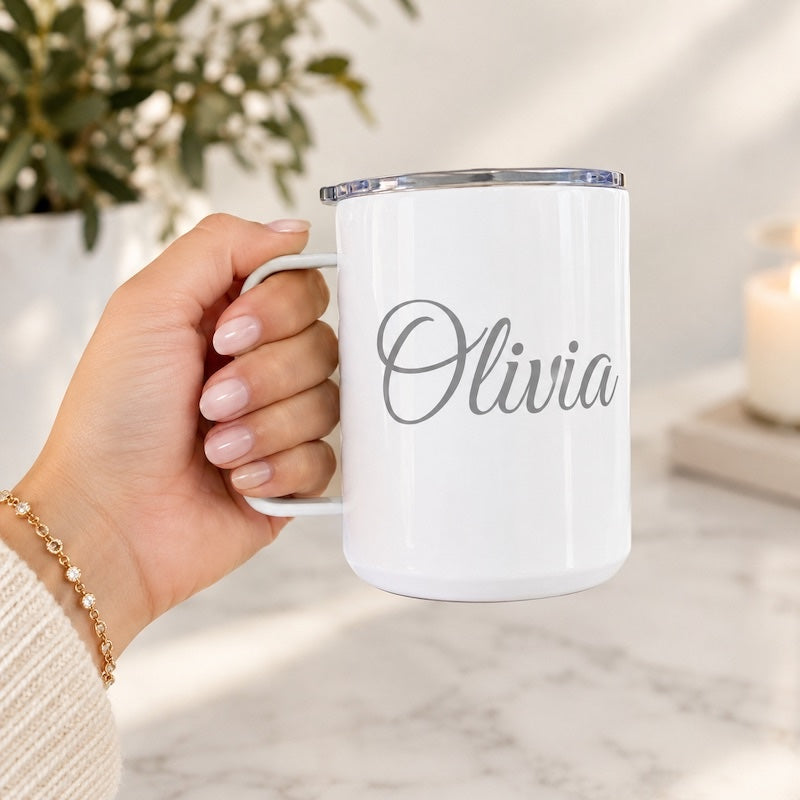 Personalized white double-wall stainless steel insulated coffee mug with clear lid, custom engraved with the name "Olivia", held in hand.