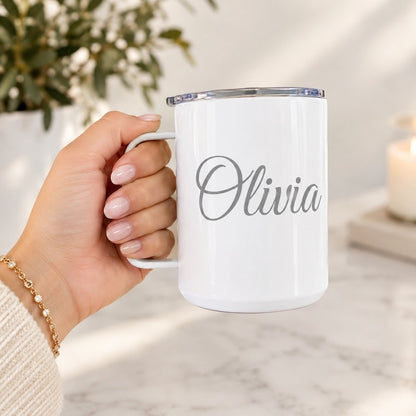 Personalized white double-wall stainless steel insulated coffee mug with clear lid, custom engraved with the name "Olivia", held in hand.