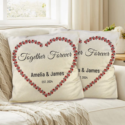 Two decorative pillows with floral heart designs and custom text on a couch.