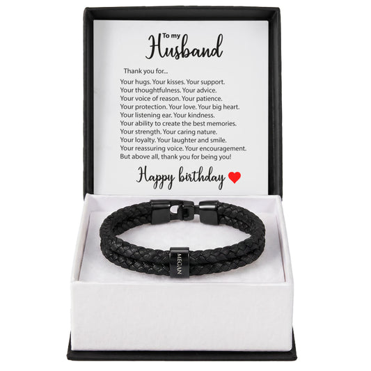 A black braided leather bracelet with a black metal clasp presented in an open white gift box with a printed message card addressed to a husband, on a white background.