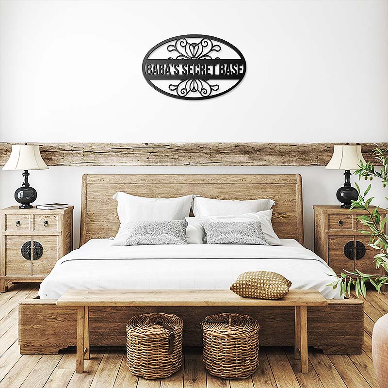 Decorative black metal sign with 'baba's secret base' text, placed on a white wall in a bedroom.