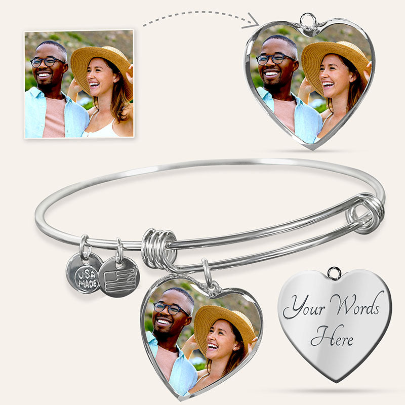 Silver engraved bangle bracelet with heart-shaped charms featuring a couple's photo and customizable text on a white background.