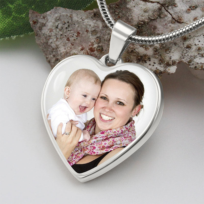 customized photo necklace: heart photo necklace with a woman and baby inside, on a textured surface.