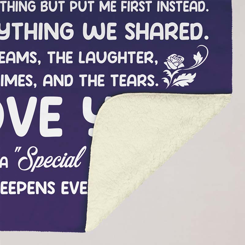 Purple blanket with white text for a mother and a rose design, showing the underside white Sherpa, on a beige background.
