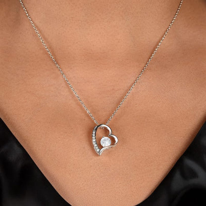 Silver heart-shaped necklace with a pendant on a person's neck